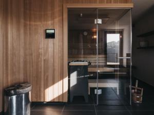 a bathroom with a glass door with a trash can at Das Dietrich - Landhaus 58 in Leibnitz