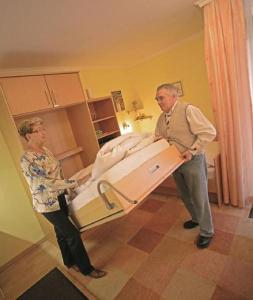 two people standing next to a bed in a room at Appartement Haus Salzburg in Bad Füssing