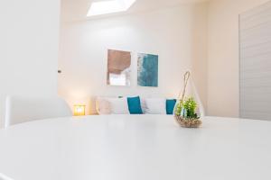 a white bedroom with a bed with a plant on it at Lumen House in Sassari