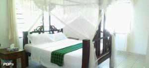 a bedroom with a bed with a canopy at Diani Horizon Beach Cottages in Diani Beach