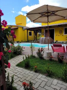 una casa con sombrilla y piscina en Pousada Céu Azul, en São Miguel do Gostoso