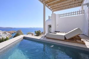 a swimming pool with a bed on the side of a house at GrandeMar Suites in Astypalaia Town