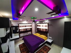 um quarto com uma cama roxa e luzes roxas em Soul Homestay em Puri
