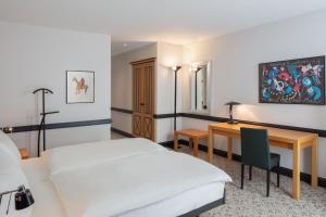 una camera d'albergo con un letto e una scrivania di Hotel Baslertor a Muttenz