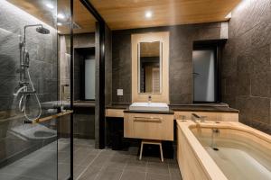 a bathroom with a tub and a sink and a shower at Grand Phenix Hakuba in Hakuba