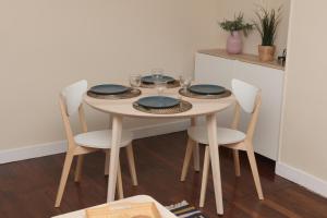 uma mesa de jantar com 4 cadeiras e uma mesa com pratos em 350 M de la gare/10min de l'hyper-centre. em Caen