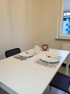 Biały stół z dwoma talerzami i kieliszkiem wina w obiekcie Apartamenty Homely - Nowowarszawska 130 w mieście Białystok