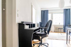 a office with a black desk and a chair at 1br apartment with patio in Lauttasaari in Helsinki