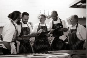 Un gruppo di uomini in una cucina che guarda un menu'. di Macdonald Houstoun House a Livingston