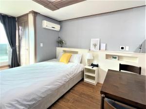 1 dormitorio con cama, escritorio y mesa en HY Choi Hostel, en Seogwipo