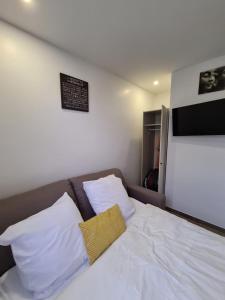 łóżko z białą pościelą i żółtą poduszką w obiekcie Studio entièrement équipé avec véranda commune w mieście Neuilly-sur-Marne