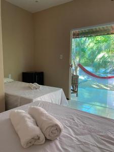 zwei Betten in einem Zimmer mit zwei Handtüchern darauf in der Unterkunft Chalés toca do guaxinim in Itarema