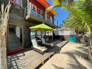 a house with a deck with two chairs and an umbrella at Mi Playa Beach Front Isabela in Puerto Villamil