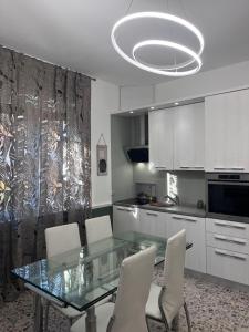uma cozinha com uma mesa de vidro e armários brancos em Casa di TAta 2 em Trezzo sullʼAdda