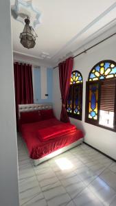 a bedroom with a red bed and two windows at Hotel Sevilla in Chefchaouene