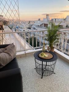 einen Balkon mit einem Tisch und Stadtblick in der Unterkunft Kolonaki 1 bedroom and 1 Sofabed Amazing Penthouse flat in Athen