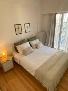 ein weißes Bett in einem Zimmer mit Fenster in der Unterkunft Kolonaki 1 bedroom and 1 Sofabed Amazing Penthouse flat in Athen