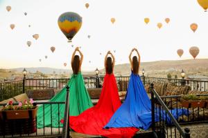 tres mujeres con vestidos coloridos mirando globos de aire caliente en Göreme Reva Hotel, en Göreme