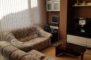 een woonkamer met een bank en een tv bij Слънчев апартамент с прекрасна гледка, паркинг. in Smolyan