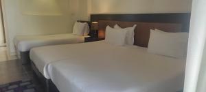 Mousa Coast Hotel & Spa في رأس سدر: غرفة فندقية بسريرين عليها شراشف ووسائد بيضاء