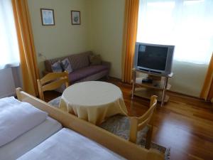 a living room with a couch and a table and a tv at Landgasthof "Altes Haus" in Waldmünchen