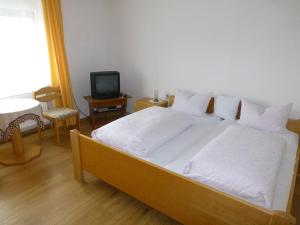 a bedroom with a bed with white sheets and a television at Landgasthof "Altes Haus" in Waldmünchen