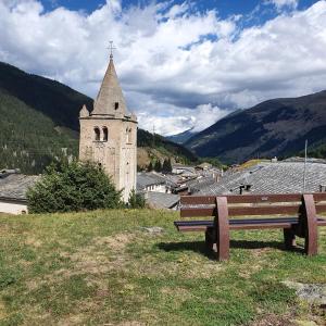 un banco sentado en la cima de una colina al lado de una iglesia en Bourg-saint-Pierre : le cachet d'antan, en Bourg-Saint-Pierre