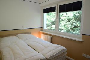 a bed in a room with two windows at La Mer Whg 03 in Wyk auf Föhr