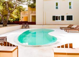 una piscina con sillas y un edificio en Apartamentos El Pino - Formentera Break, en Es Caló