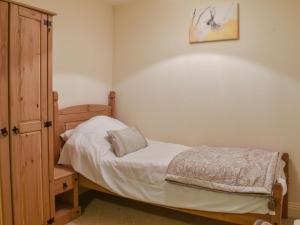 um pequeno quarto com uma cama e um armário de madeira em South Wing Coldharbour Park Farm em Rake