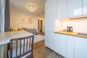 a kitchen and living room with white cabinets and a table at Žalgiris arena apartment with AC in Kaunas
