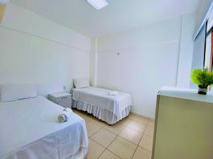 a white room with two beds and a tv at Beverly Hills por Be My Guest in Aquiraz +42 photos