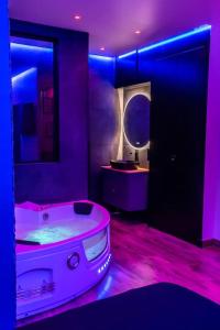 uma casa de banho roxa com uma banheira e um espelho em BLUE NIGHT - Jacuzzi - Bord de Seine em Corbeil-Essonnes