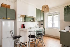 a kitchen with green cabinets and bar stools at DIFY Central - Bellecour in Lyon