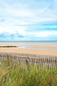 uma vista para uma praia com uma cerca de madeira em Thalazur Cabourg - Hôtel & Spa em Cabourg