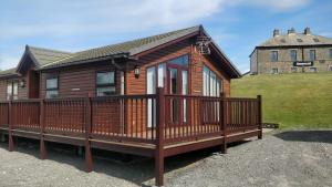 a large wooden house with a large deck at Lake View Lodge in Millom