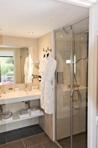 a bathroom with a shower and a white robe at Thalazur Cabourg - Hôtel & Spa in Cabourg