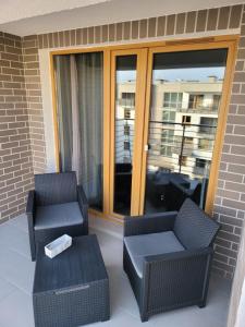 two chairs and a table on a patio with a window at Apartamenty Tenisowa in Szczecin