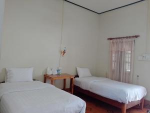 um quarto com duas camas e uma mesa e uma janela em Meexai Guesthouse em Nongkhiaw