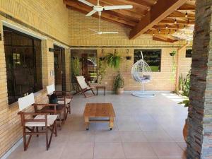 eine Terrasse mit Tischen und Stühlen sowie einem Ventilator in der Unterkunft Casa con Piscina, Quincho, Cancha de Futbol/Volley in San Bernardino