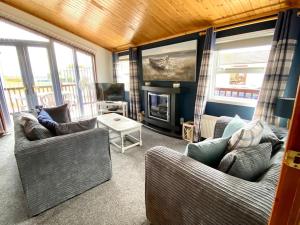 sala de estar con 2 sofás y chimenea en Lake View Lodge en Millom