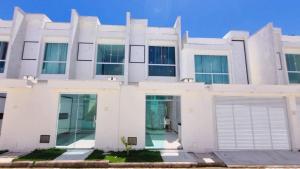 Apartamento a 400 metros da praia de taparapuan في بورتو سيغورو: منزل أبيض مع مرآب للسيارات