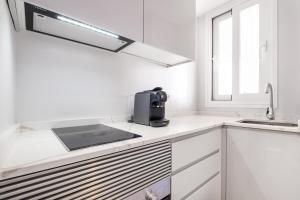 eine weiße Küche mit einer Spüle und einer Mikrowelle in der Unterkunft Mara Boutique Apartments in Benidorm