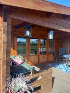 a porch of a wooden cabin with a couch at jacuzzi cows dairyfarm relaxing sleeping in Hitzum