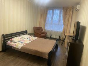 ein Schlafzimmer mit einem Bett, einem Stuhl und einem TV in der Unterkunft Apartment on Akhmatovoyi 32/18 in Kiew