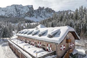 un edificio cubierto de nieve con montañas de fondo en Residence Chris Appart, en Carezza al Lago