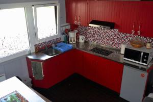 cocina roja con fregadero y microondas en Cocooning Auvergnat, en La Bourboule