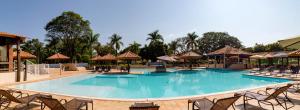 une grande piscine avec des chaises et des parasols dans l'établissement Santa Eliza Eco Resort, à Ribeirão Bonito