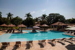 a large swimming pool with chairs and umbrellas at Santa Eliza Eco Resort in Ribeirão Bonito