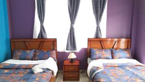 2 Betten in einem Schlafzimmer mit lila Wänden in der Unterkunft Tariang's Enclave Homestay in Shillong